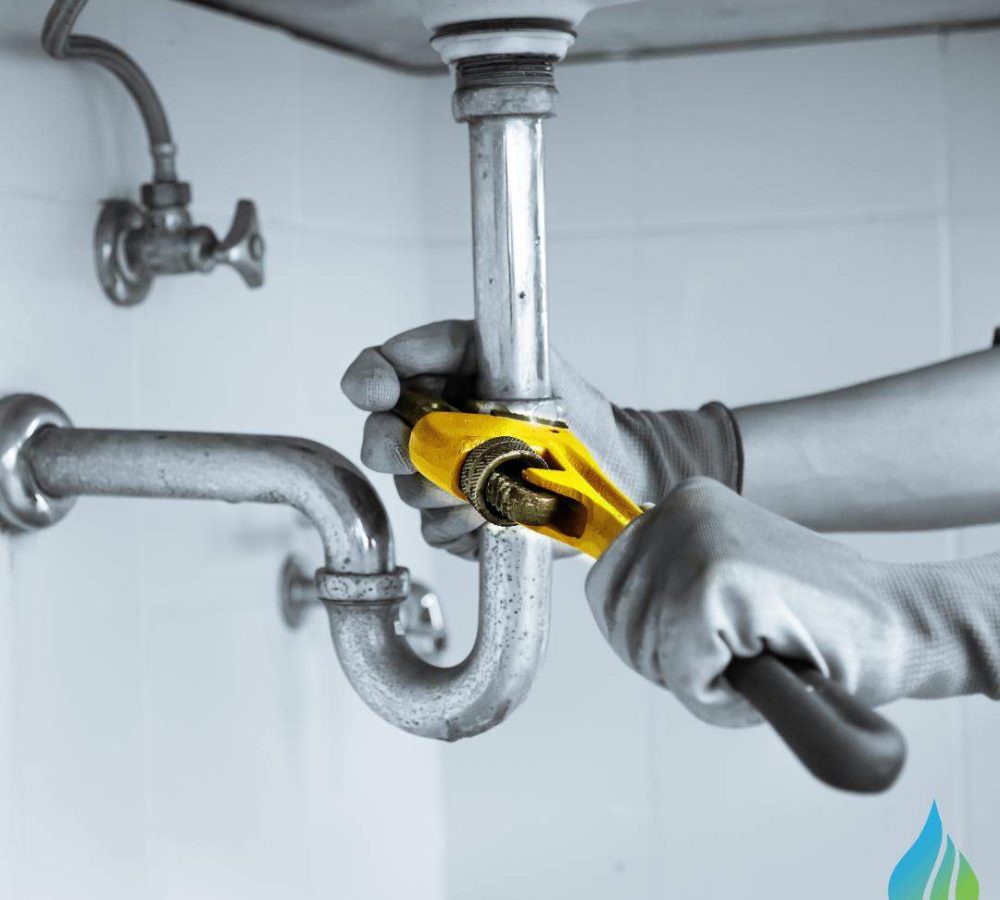 professional with gloves working on plumbing leak under sink