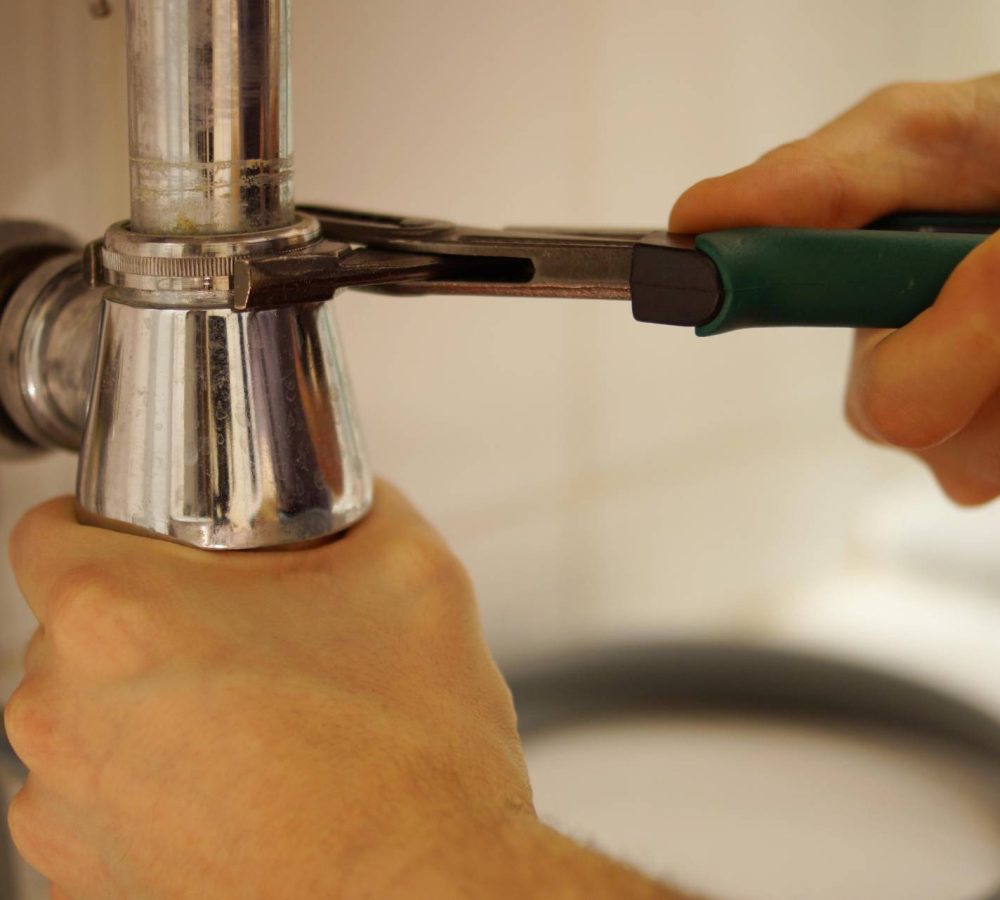 professional doing plumbing work on kitchen sink