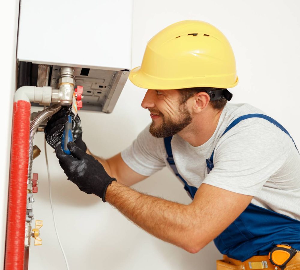 professional in yellow work hat installing water heater